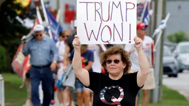 a woman holds up a QAnon sign