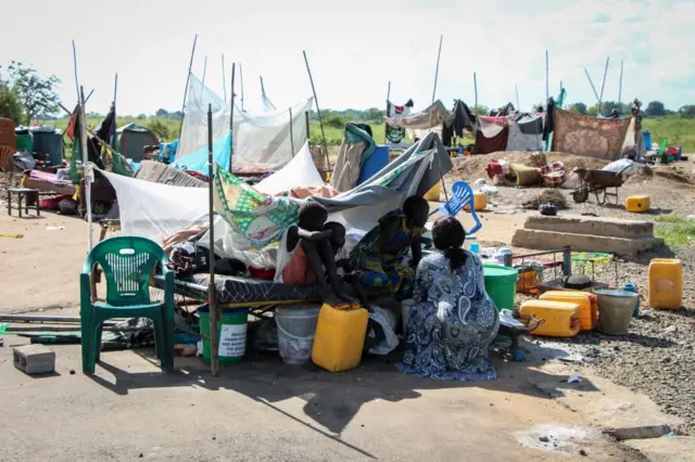 Displaced villagers stay with their belongings along a road after being evacuated from flooded water in Juba, South Sudan, on September 28, 2021