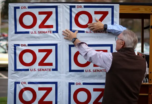 A supporter of Pennsylvania Republican US Senate candidate Dr Mehmet Oz fixes posters