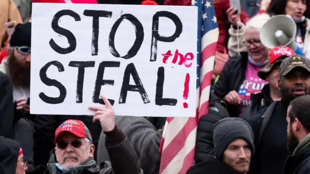 A man holding a sign saying "Stop the Steal"