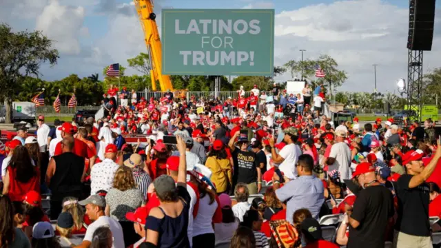 Trump attendees beneath a Latinos for Trump sign