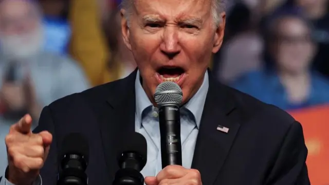 President Joe Biden points his finger while speaking into a microphone