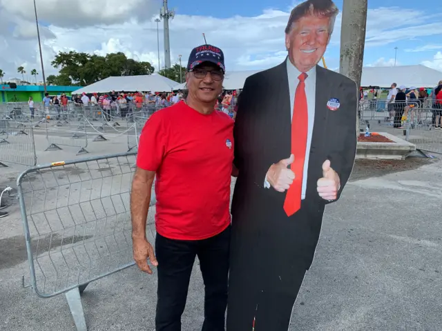 A man carrying a cardboard cutout of Trump