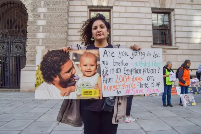 Sanaa Seif holding a picture of her brother and a placard asking if the UK government will let her brother die in prison, during a demonstration outside the Foreign Office in London in October 2022