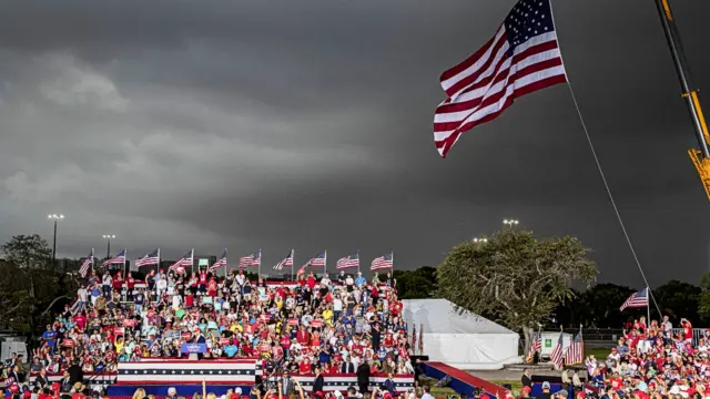 A crowd of people listen to former president Donald Trump speaking at a rally in Florida