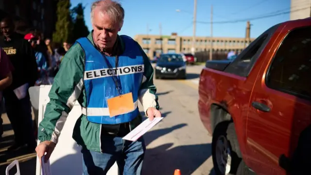 An official ballot collector for the Cuyahoga County Board of Elections deposits voters' mail-in ballots into a collection box in Cleveland, Ohio on November 6, 2022