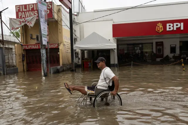 A man in a wheelchair making his way through flooded parts of the Philippines