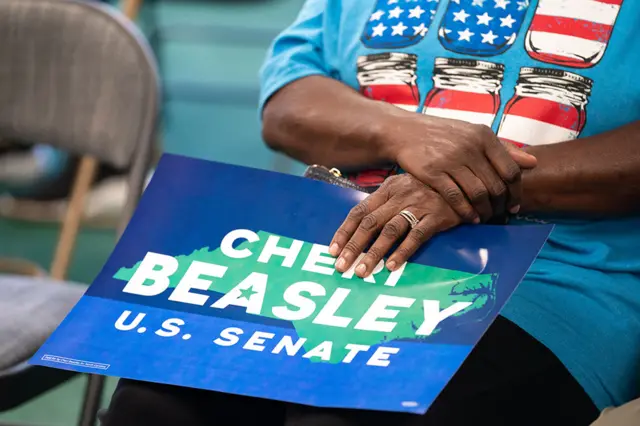 A woman holds a campaign sign while listening to Democratic US Senate candidate Cheri Beasley during a canvassing event on 7 November 2022 in Winston-Salem, North Carolina, US