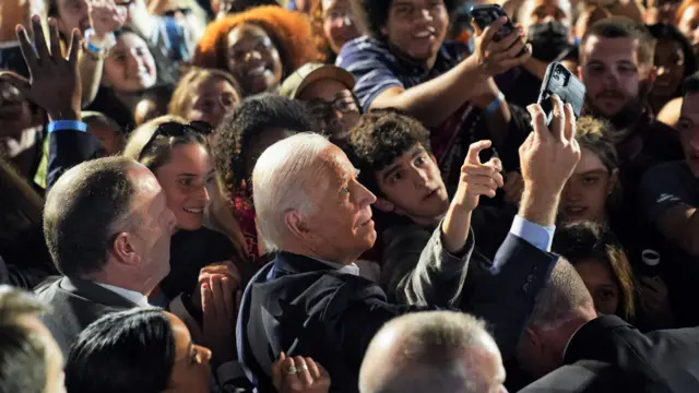 Joe Biden takes a selfie with supports in a crowd of people during a campaign rally