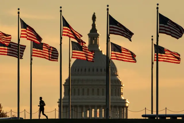 A jogger passes US flags on the National Mall in front of the Capitol Building