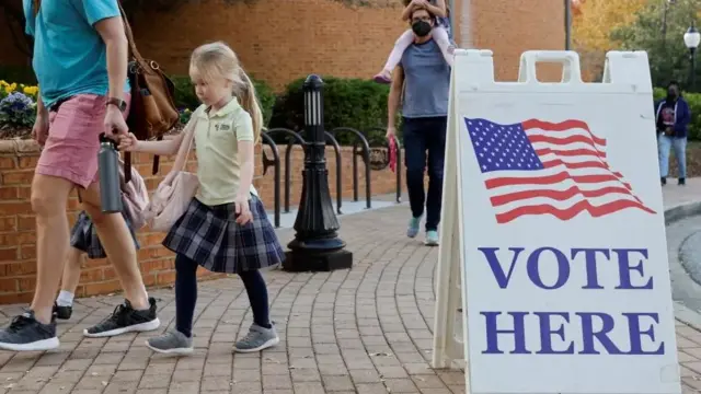 A girl walks into a polling station holding hands with her parent