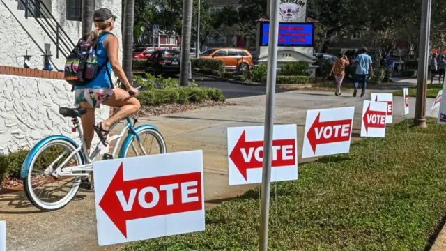 A cyclist rides past vote signs during the US midterm election, in Tampa, Florida, on November 8, 2022