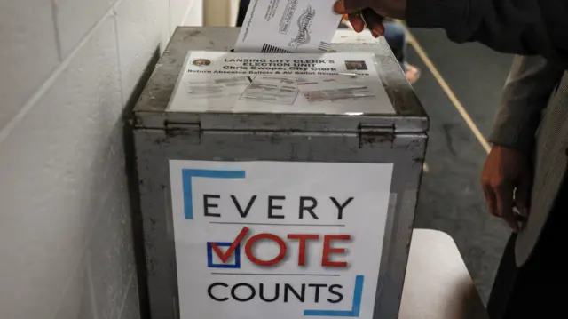 An early voter drops his ballot paper in a voting box in Michigan