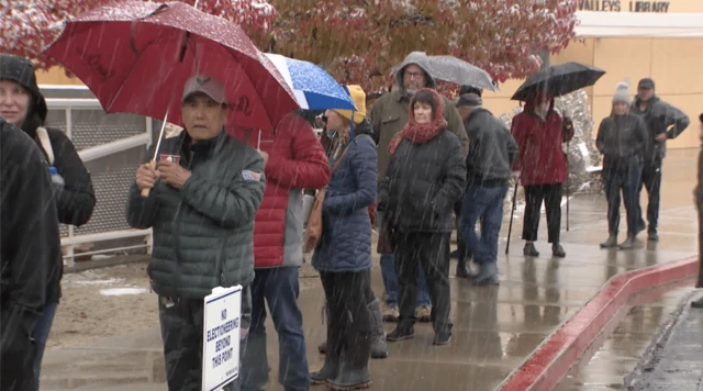 Voters waiting to vote while holding umbrellas to shield themselves from the snow