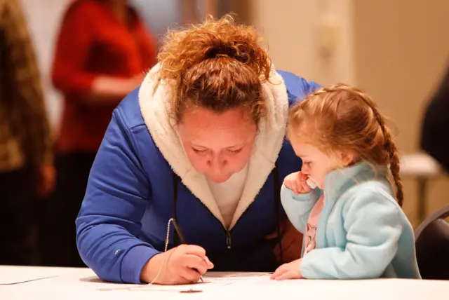 A woman fills out her ballot as her niece looks on