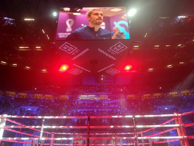 Shot from in front of the ring with a football game being shown above