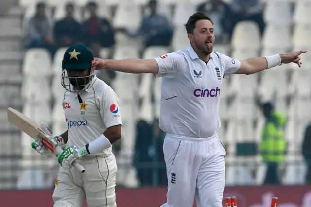 Ollie Robinson (R) celebrates after taking the wicket of Pakistan's captain Babar Azam (L) during the second day of the second cricket Test match between Pakistan and England at the Multan Cricket Stadium in Multan on December 10, 2022