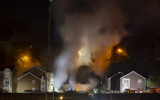 A night time image of smoke coming from the remains of a building