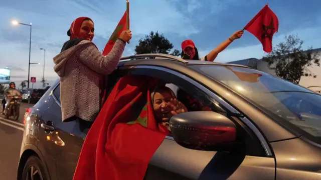 Morocco fans in Casablanca wave flags from a car as they celebrate progressing to the semi-finals of the World Cup on 10 December 2022