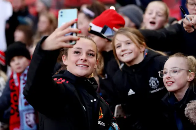 Manchester United's Ella Toone takes a picture with some fans after their game at Old Trafford against Aston Villa