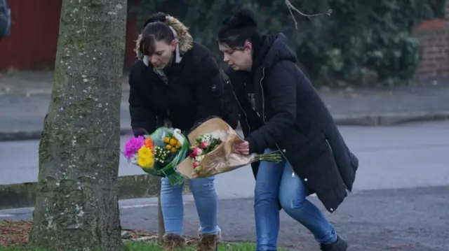 Members of the public laying flowers in Babbs Mill Park in Kingshurst, Solihull
