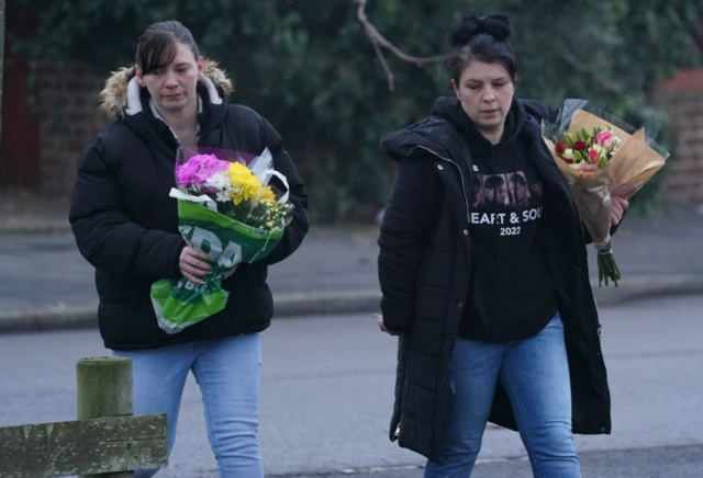 Two women lay flowers near Babbs Mill Park