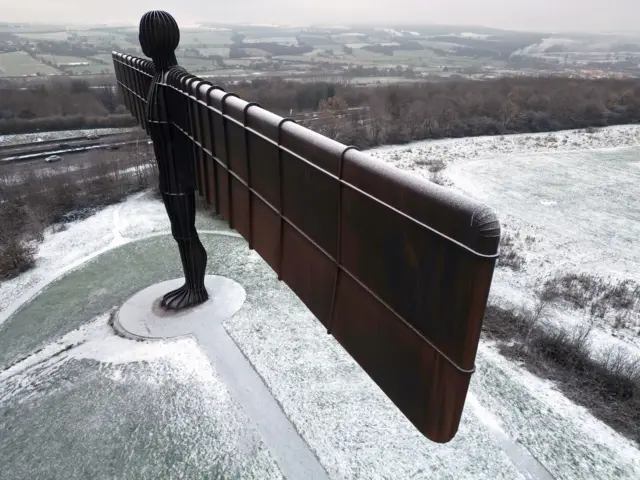 Angel of the North statue, dusted with snow - seen above with snow and ice in the surrounding grass and oaths