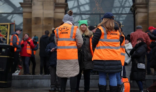 People stand on a Rail, Maritime and Transport Workers (RMT) picket line outside Lime Street Station