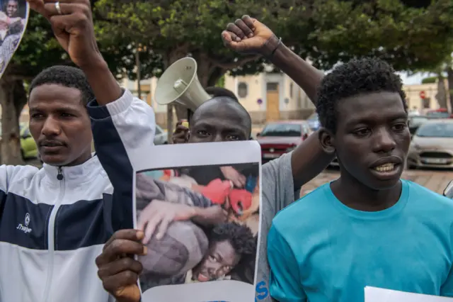 Protesters in Melilla, Spain, hold photos appearing to show migrants being attacked.