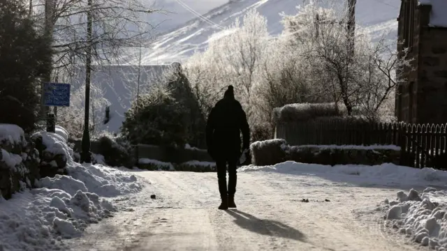 A man walks on a snow covered road in Braemar, Scotland, Britain December 13, 2022.