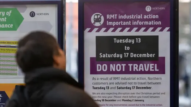 People look at signs giving information about industrial action at Victoria Station in Manchester