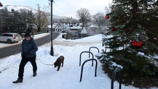 A man walks a dog in Braemar, Scotland, Britain December 13, 2022.