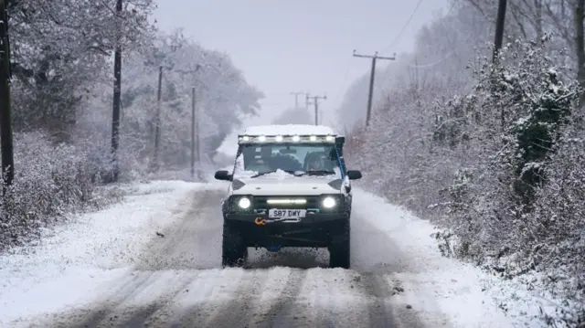 A four-wheel drive car drives along an icy road in Ashford, Kent