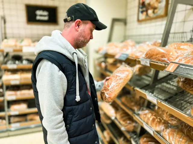 Man looking at bread in supermarket