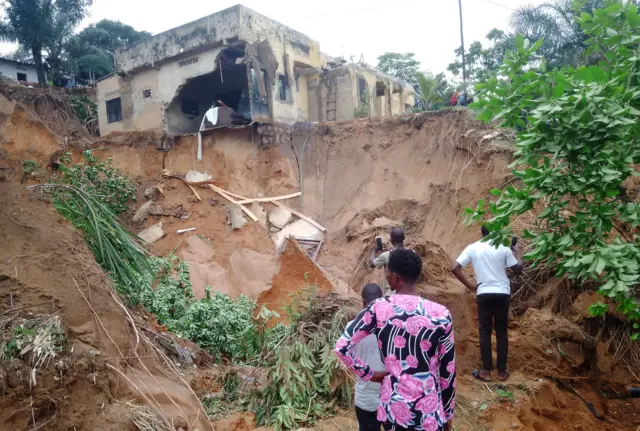 People stand watch after heavy rains caused floods and landslides, on the outskirts of Kinshasa, Democratic Republic of Congo December 13,2022.