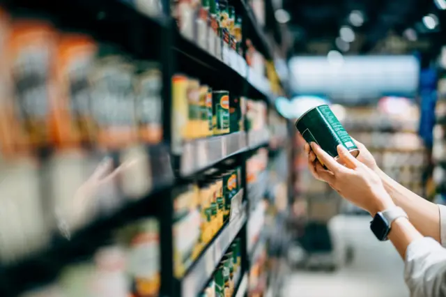 Person holds a tin can in a supermarket