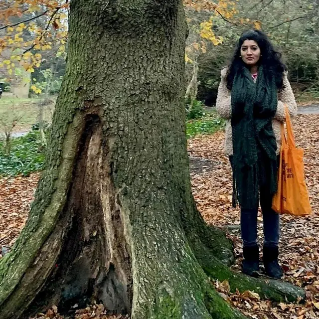 Zara Aleena, standing next to a large old tree, surrounded by autumnal leaves