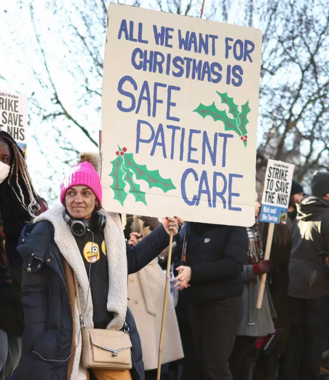 A woman holds a sign saying all she "wants for Christmas is safe patient care".