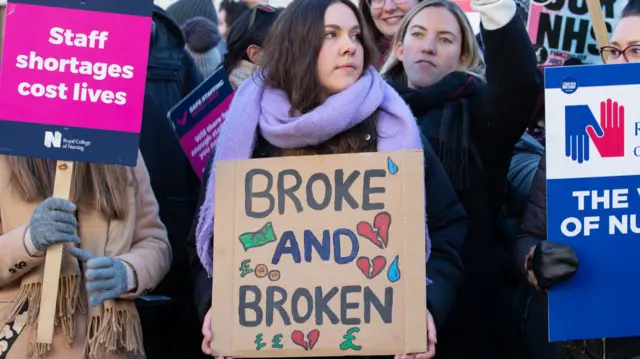 A nurse in London holds a placard saying nurses are "broken and broken"