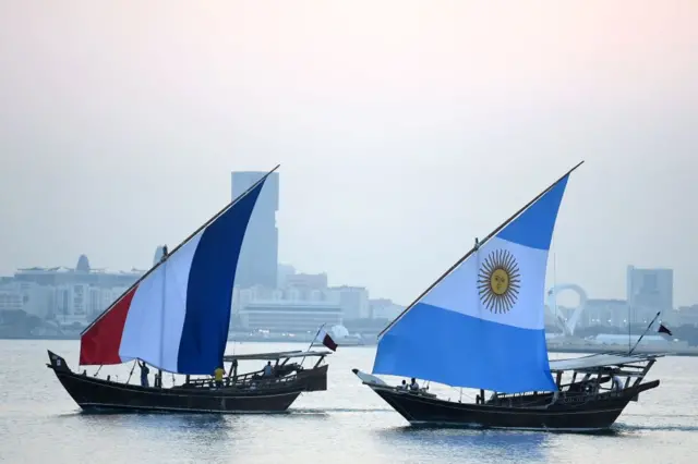 Boats with flags of France (L) and Argentina sail along the Corniche seafront in Doha