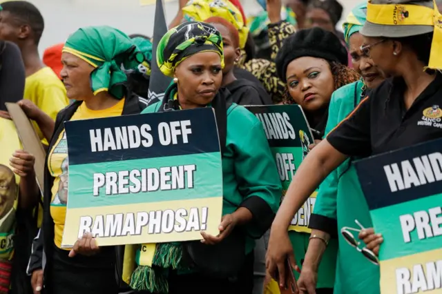 Supporters of South African President Cyril Ramaphosa hold placard