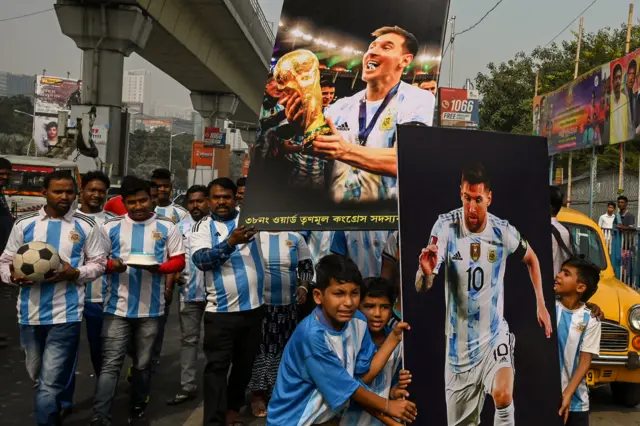 Fans in India carry a Lionel Messi poster through India