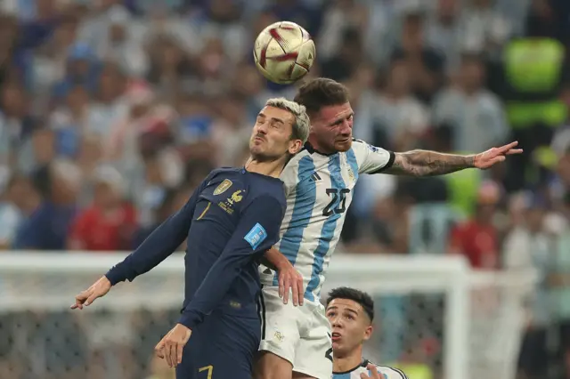 Antoine Griezmann challenges Alex Mac Allister in the air for a header