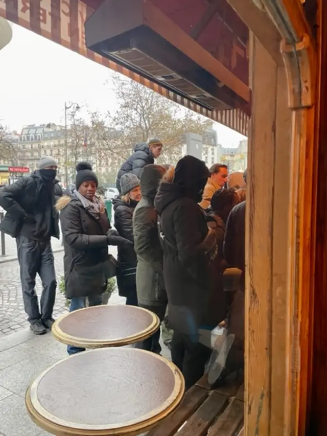 Passers-by crowding around windows of packed bar to watch the World Cup final from the street in Paris