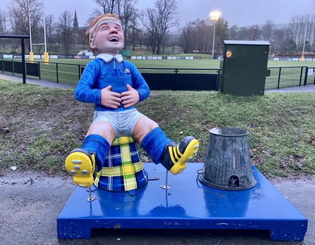 Oor Wullie decked in the My Name5 Doddie Foundation tartan greets well-wishers at the gates of The Greenyards