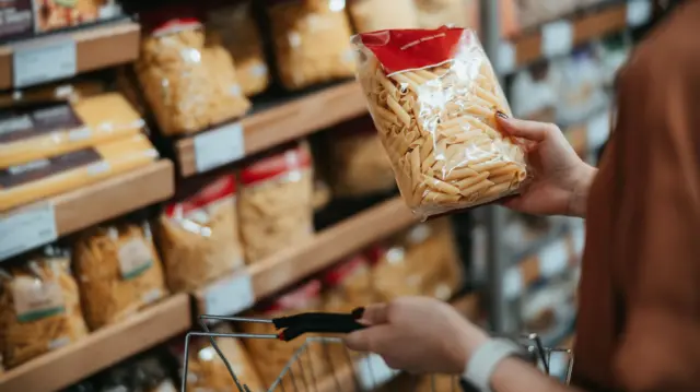 Customer buys dry pasta in a supermarket