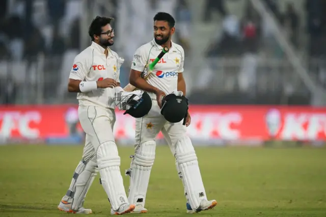 Abdullah Shafique and Imam Ul-Haq walking off the field at close on day two