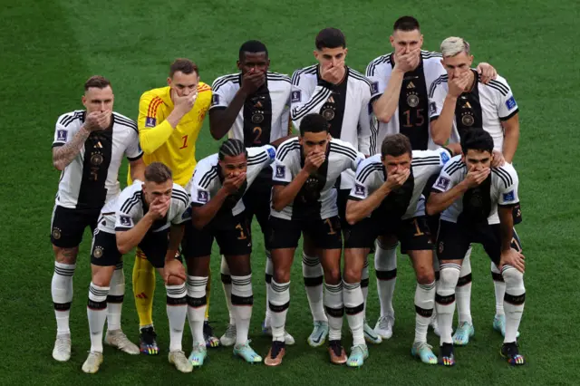 Germany players pose with their hands covering their mouths as they line up for the team photos