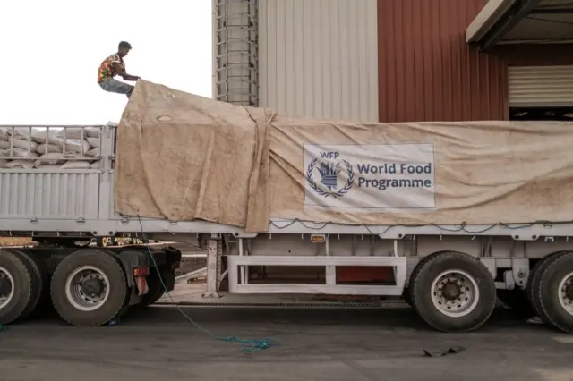 A worker covers WHO sacks of grain.