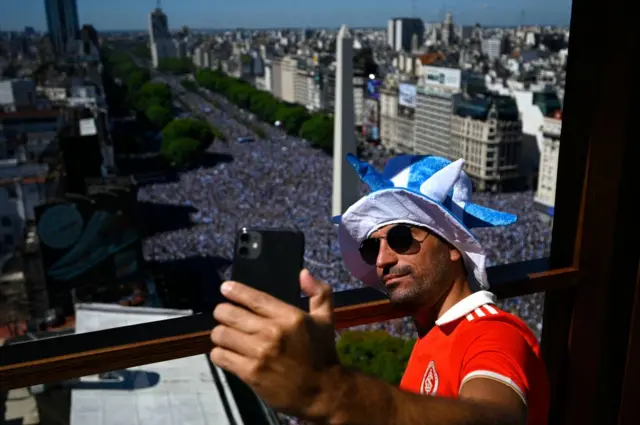 A man takes a selfie near the Obelisk, while Argentine supporters wait for the bus with Argentina's players to pass through